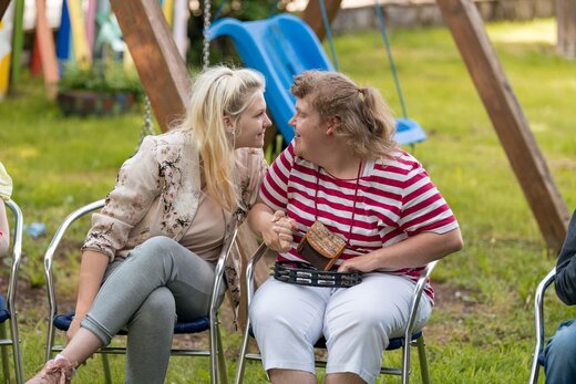 Betreuerin und Frau mit Behinderung sitzen im Garten