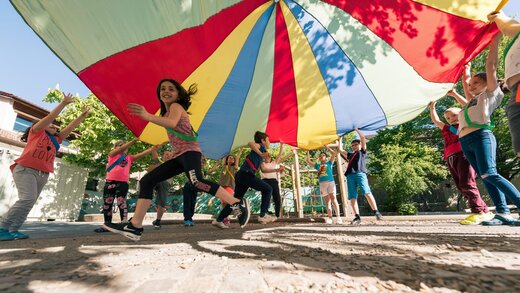 Kinder spielen mit einem Fallschirm-Schwungtuch