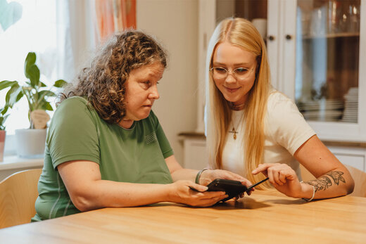 Eine Klientin mit Sehbehinderung und ihre Bertreuerin schauen in ein Handy