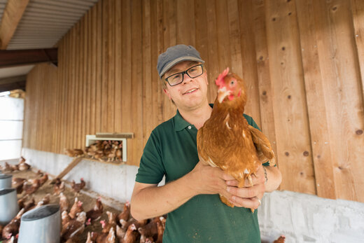 Junger Mann mit Huhn aus der Landwirtschaft