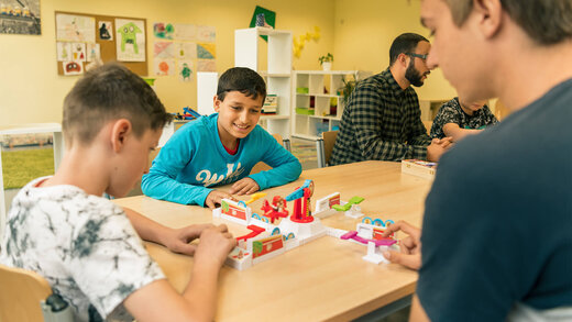 Drei Jungs sitzen gemeinsam am Tisch und spielen