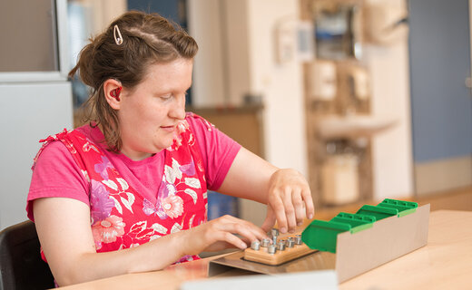 Frau macht Montagearbeiten in Werkstatt für Menschen mit Behinderung