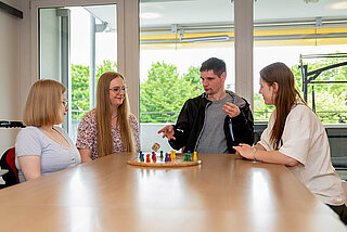 Vier junge Menschen beim Spielen eines Brettspiels für Menschen mit Sehbehinderung