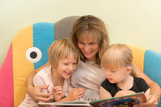 Erzieherin liest ein Buch mit zwei Kindern der Kindergarten der Stiftung St. Franziskus