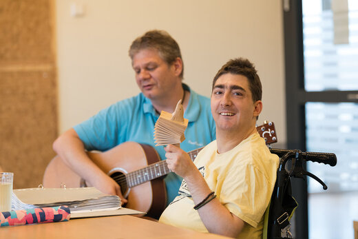 Betreuer und Mensch mit Behinderung machen gemeinsam Musik 