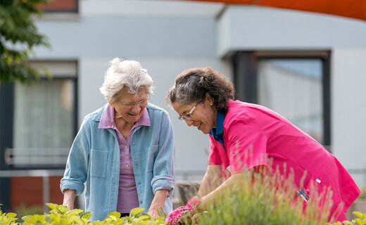 Seniorin und Betreuerin arbeiten im Garten 