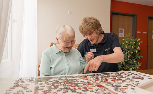 Seniorin und Pfleger puzzeln gemeinsam 