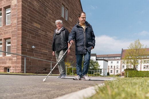 Mann mit Behinderung läuft mit Blindenstock