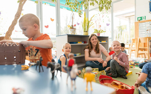 Kinder spielen gemeinsam mit Betreuerin in der Kindertagesstätte