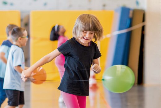 Mädchen spielt mit Luftballon in Schulsporthalle für Kinder mit Sinnesbehinderung