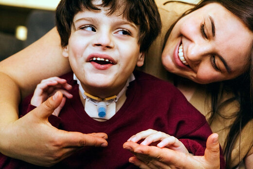 Jugendlicher mit Taubblindheit bekommt von Betreuerin, die hinter ihm steht in die Hände gelormt