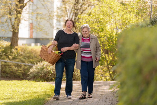 Seniorin und Betreuerin gehen gemeinsam spazieren