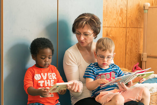 Frau schaut gemeinsam mit zwei Kindern Bücher an 