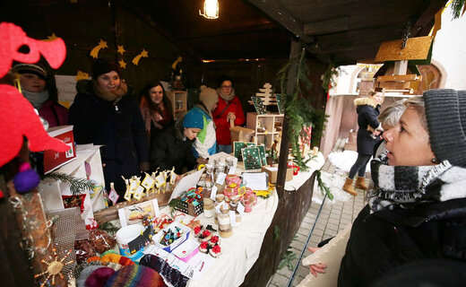 Blick beim Adventsmarkt in eine Hütte mit Besucherin im Vordergrund