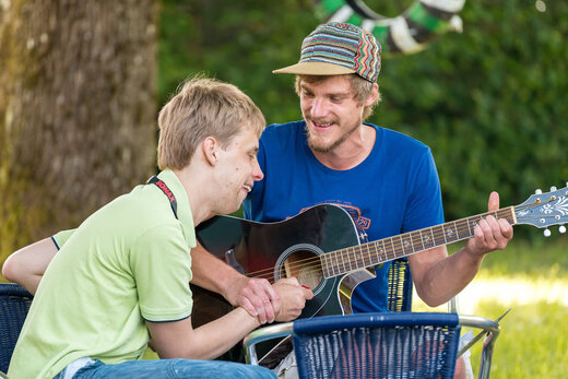 Betreuer spielt gemeinsam mit Junge Gitarre