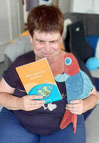 Autorin Sabine Ludi mit ihrem Buch "Mein Leben als Blindfisch" und einem Stoff-Fisch in den Händen