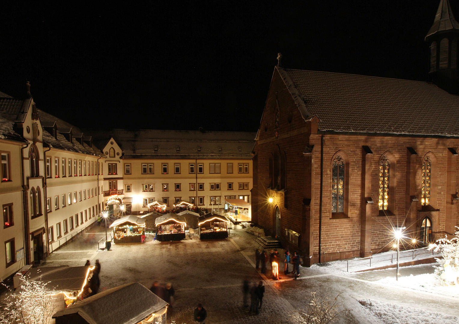Blick in den verschneiten Klosterhof mit Hütten beim Adventsmarkt