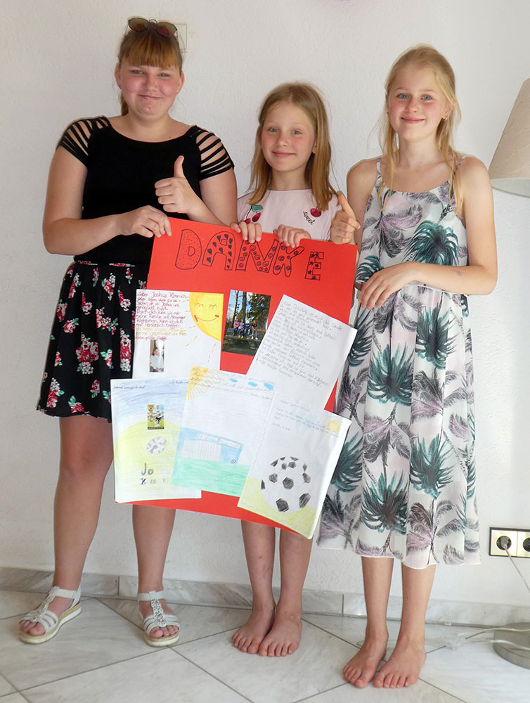 Drei Mädchen mit einem "Danke"-Plakat in den Händen
