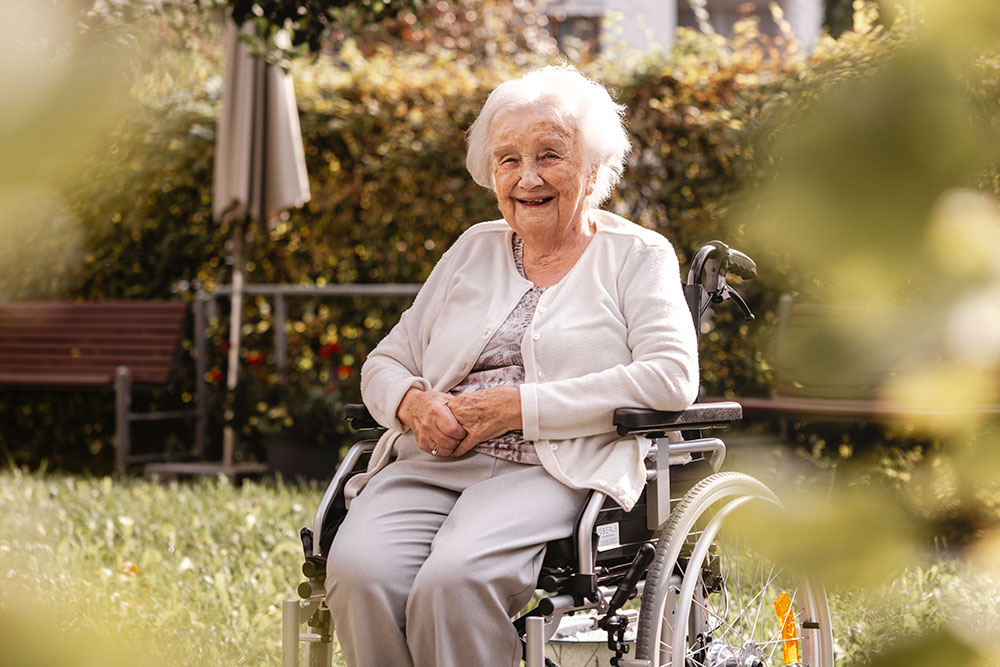ältere Dame im Rollstuhl sitzend im Garten