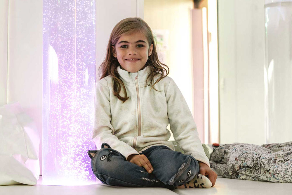 Ein Mädchen im Snoezelraum sitzend entspannt sich