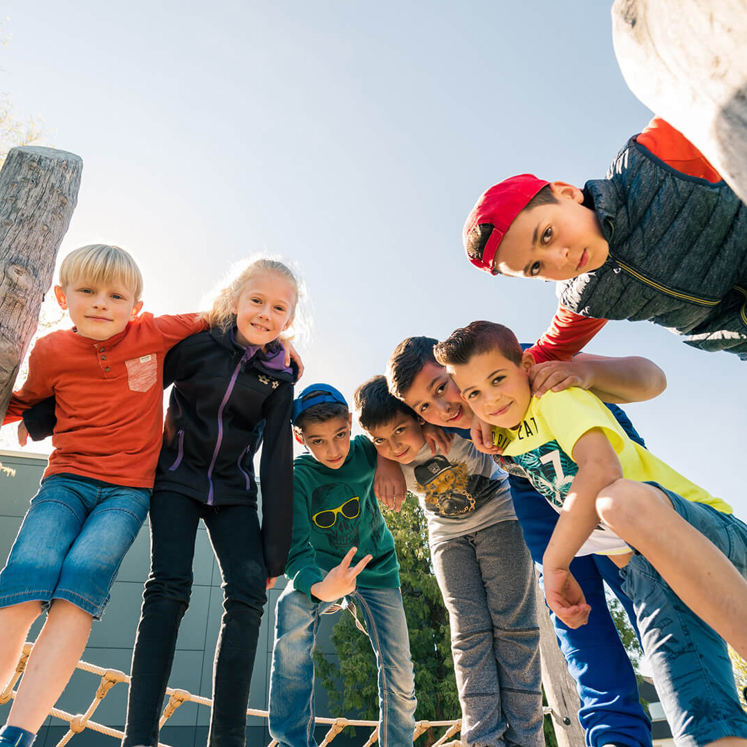 mehrere Kinder umarmen sich und gucken lachend in die Kamera