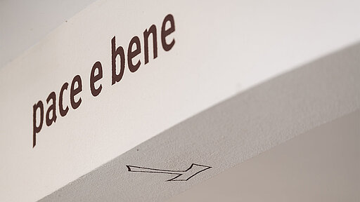 "pace e bene"-Schriftzug und franziskanisches Tau im Torbogen Heiligenbronn